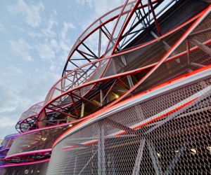 A sweeping red architectural curve beneath a pale blue sky